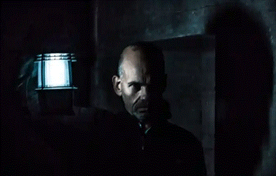 A man holds a lit lantern in a dark stone room. A man holds a lit lantern in a dark stone room.