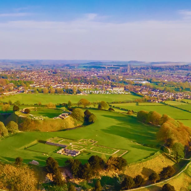 An aeiral view of an Iron Age Hill fort surrounded by fields and houses.