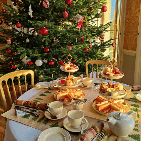 A festive afternoon tea set up with a Christmas tree in the background A festive afternoon tea set up with a Christmas tree in the background