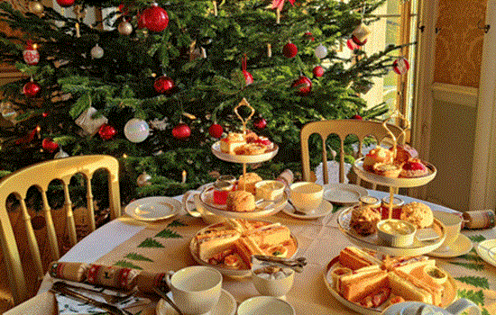 A festive afternoon tea set up with a Christmas tree in the background A festive afternoon tea set up with a Christmas tree in the background