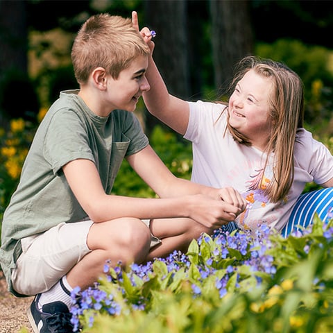 A boy and a girl play with flowers