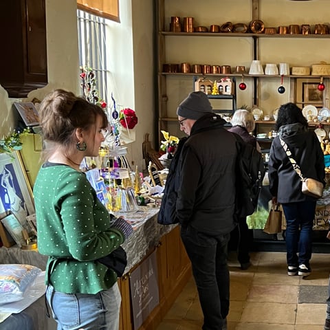 People browsing stalls at an indoor Christmas market at Audley End in the kitchens.