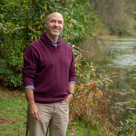 Author Jim Costa smiles standing next to a lake.