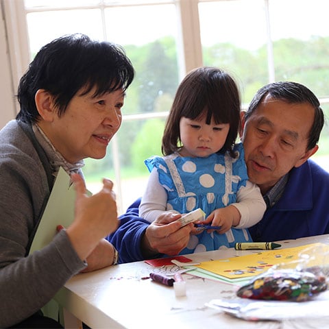 Two adults and a young child do some craft activities