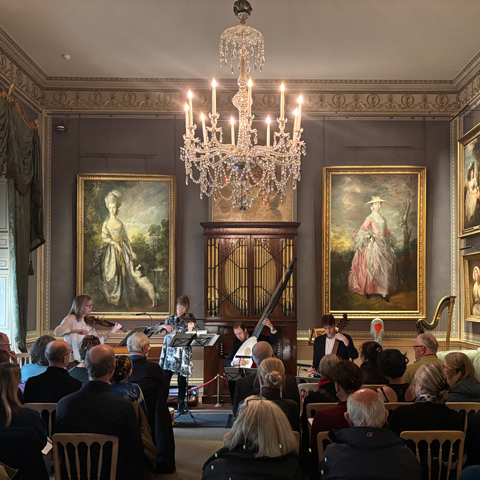 A live band plays in the music room at Kenwood in front of a seated audience.