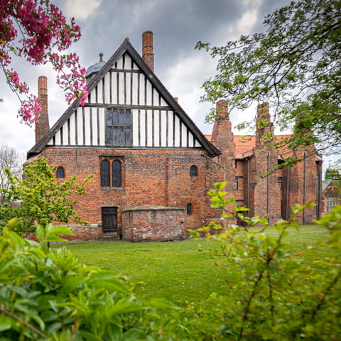 An exterior view of Gainsborough Old Hall through the trees.