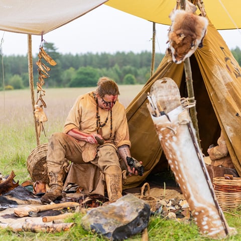 A man demonstrates flintknapping in a workshop.