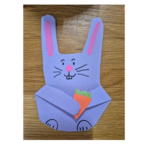A purple card handmade bunny holding a carrot.