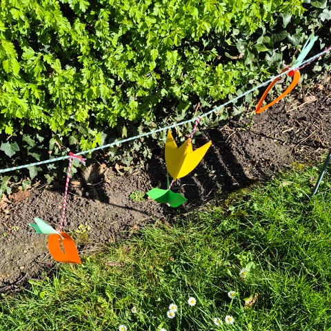 A string of spring themed bunting hanging with grass in the background.