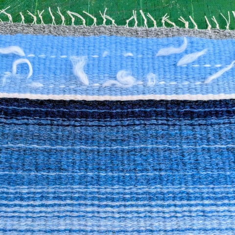 A close up of a colourful blue and white woven fabric.