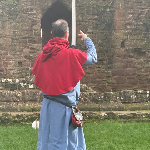 A reenactor holds a sword demonstrating in the grounds of Goodrich Castle.