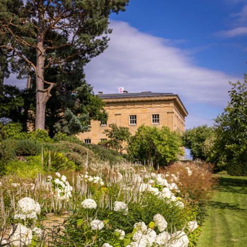 A view of Belsay Hall with flowers in the foreground.