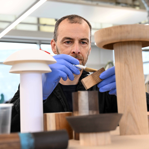 A man varnishes blocks of wood