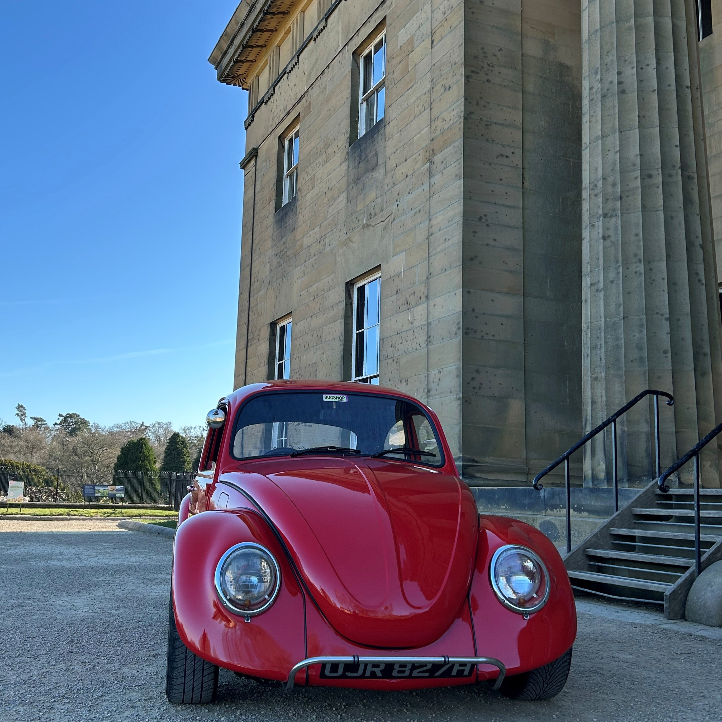 A red VW parked in front of Belsay Hall on a sunny day.