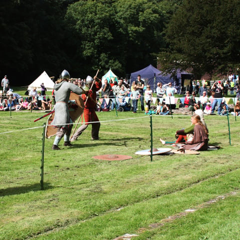 A medieval fight re-enactment in the grounds of Furness Abbey with a large crowd gathered.
