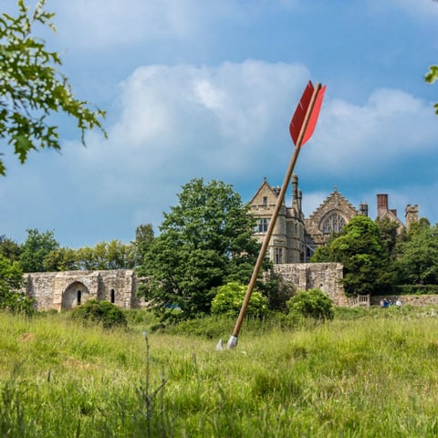 A view of Battle Abbey on a sunny day with a red arrow in the foreground stuck in the ground.