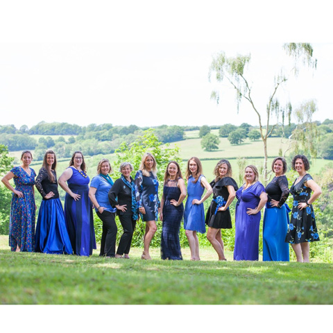 A photo of the Cantando Choir standing on a lawn all dressed in blue.