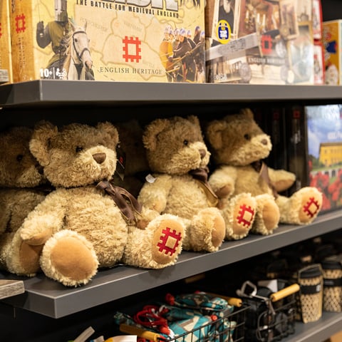 Board games and English Heritage branded teddy bears on a shop shelf.