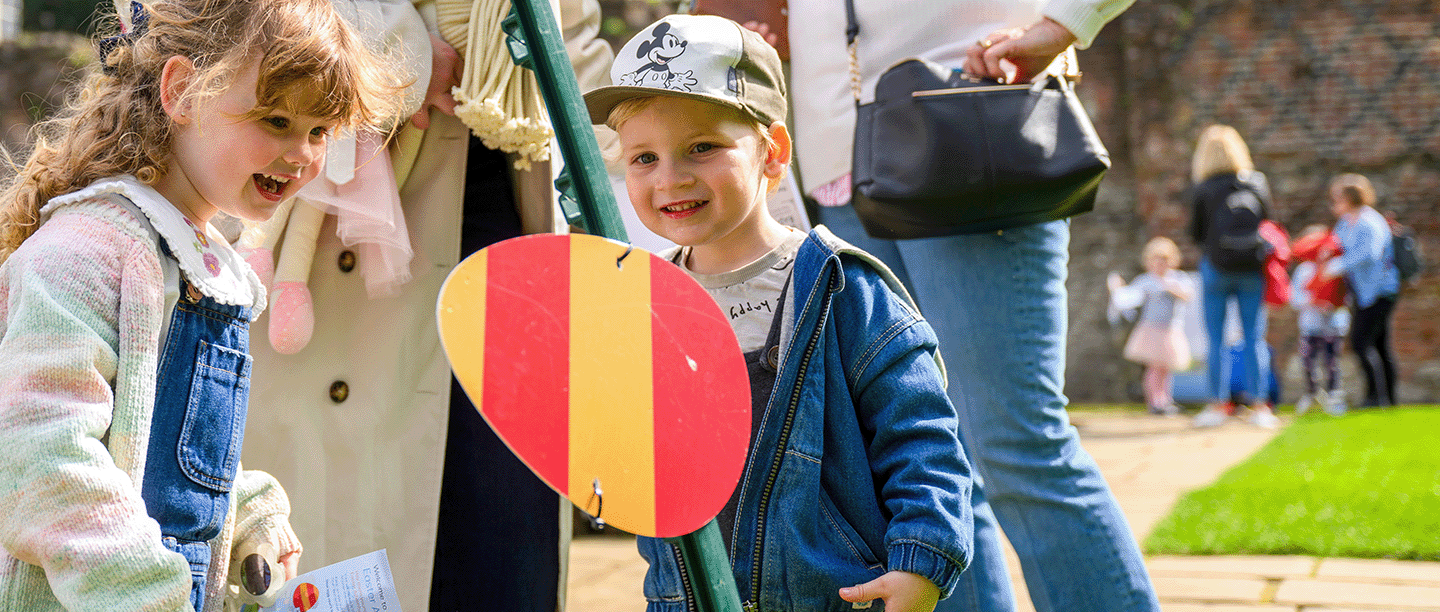 Photo of two young children and two adults looking at an Easter-egg-shaped waymarker in the gardens of Eltham Palace in London