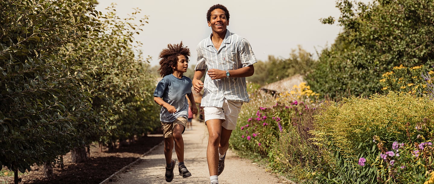 An older and younger child run through the gardens at Walmer Castle on a sunny day.